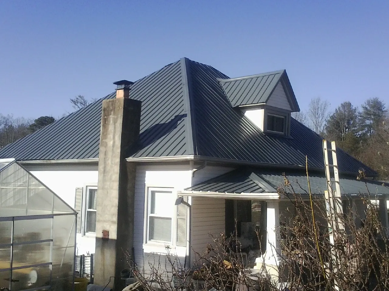 Dark blue standing seam metal roof on a white farmhouse with dormer — Slate & Tile Roof Repair by Roofing Brothers in Steger