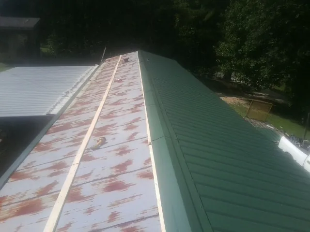 Old rusted panels beside newly installed green metal roofing — Wind Damage Roof Repair by Roofing Brothers in Steger