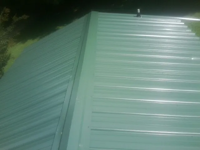 New green metal panels meeting at the ridge of a roof — Flat Roof Repair work by our crew in Steger