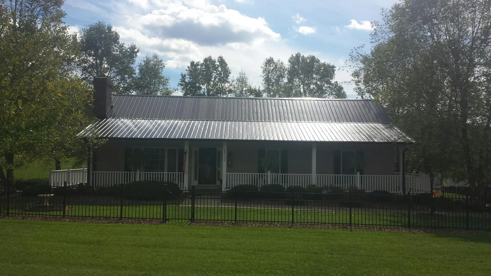 Gray metal roof on a brick ranch with a full width front porch — Gutter Guard Installation work by our crew in Steger