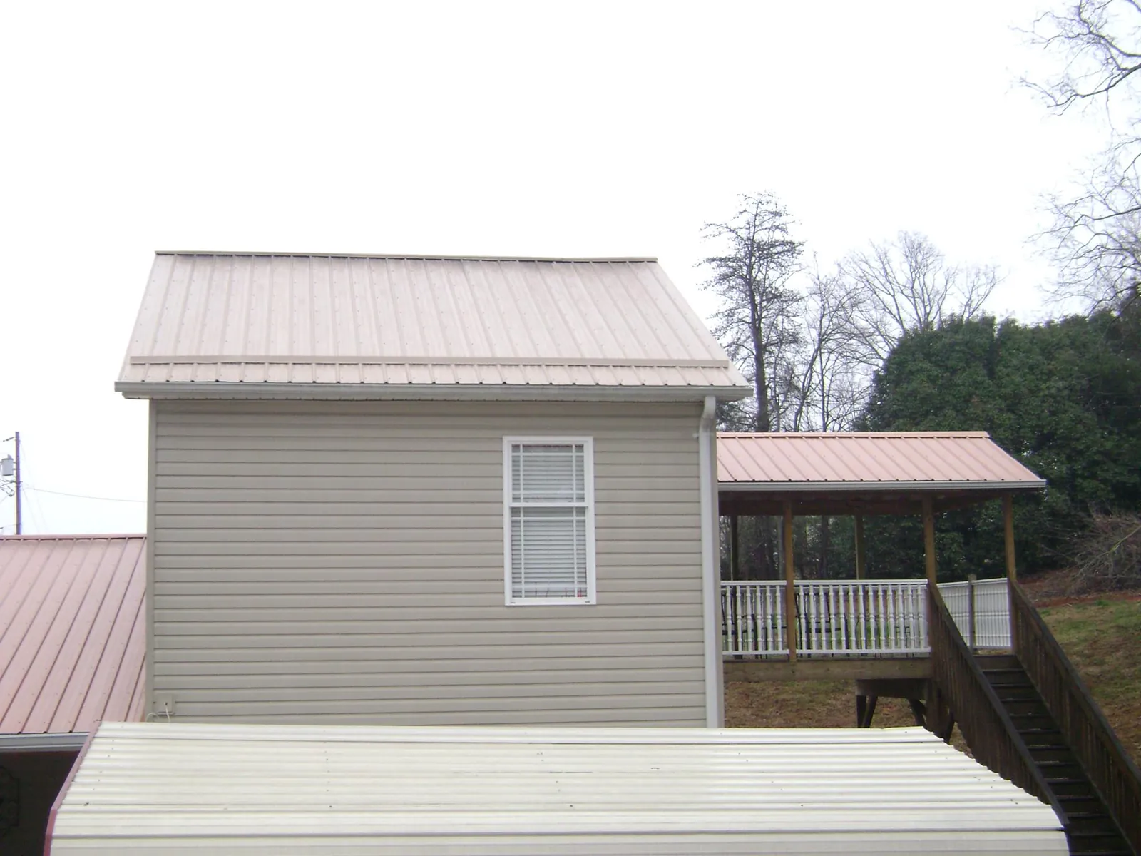 Tan metal roofs on a two story addition and attached porch, from a Roof Replacement job in Steger